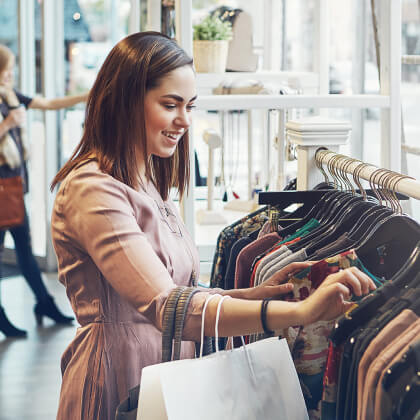 A young woman looking through a rack of clothes in a store