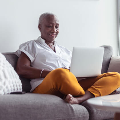 A woman sitting on a couch with a laptop
